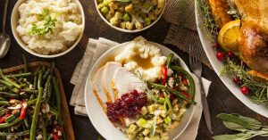 Photo of a holiday feast on a table with turkey. stuffing, mashed potatoes, gravey and green beans.